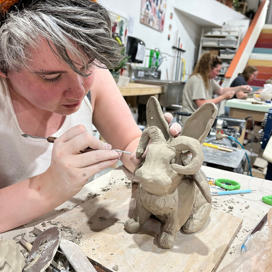 Person working on a clay sculpture in a workshop setting
